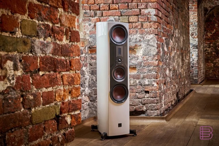 High-end floorstanding loudspeaker against an exposed brick wall