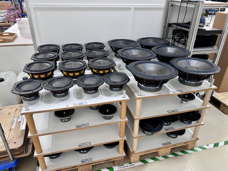 Rows of Bowers & Wilkins mid-woofer and bass drive units on a factory shelf