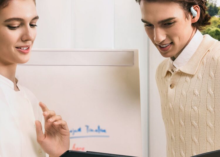 Shokz OpenFit Air 2 open-ear earbuds worn by two colleagues in an office
