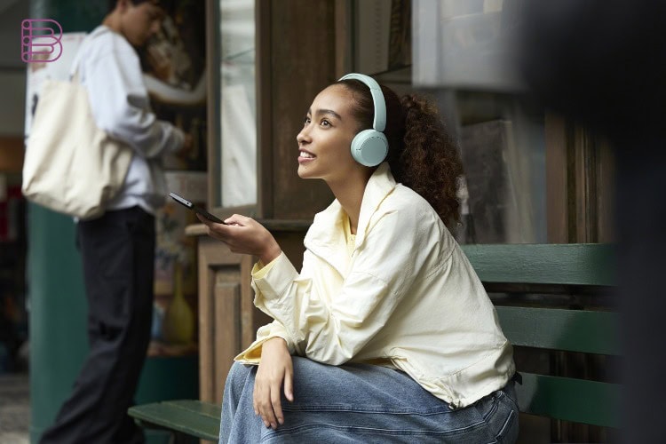 Person wearing Sony WH-CH530 headphones in Mint while sitting outdoors
