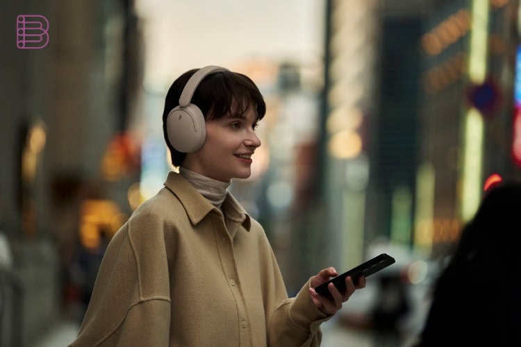 Person wearing Sony WH-CH730N headphones in Beige while walking through a city street