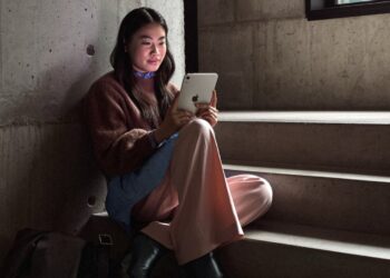 Woman using the new Apple iPad mini with OLED display on a staircase