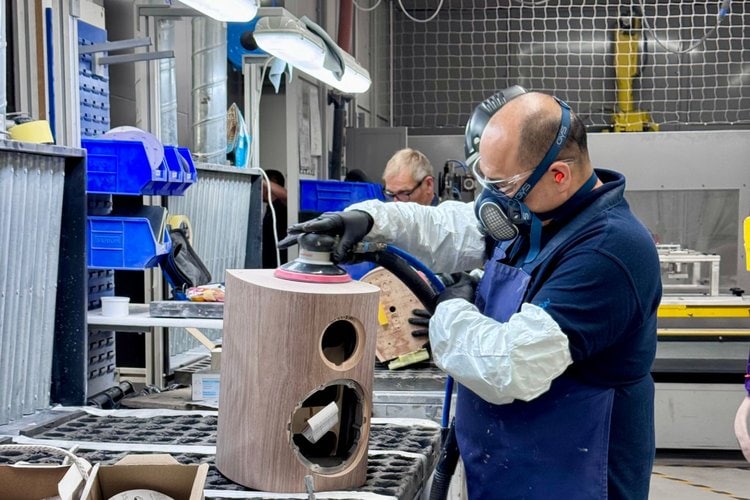 Craftsman hand-sanding a walnut loudspeaker cabinet