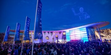ISE 2027 venue at twilight with a drone light show and crowd gathered outside