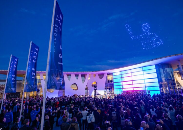 ISE 2027 venue at twilight with a drone light show and crowd gathered outside